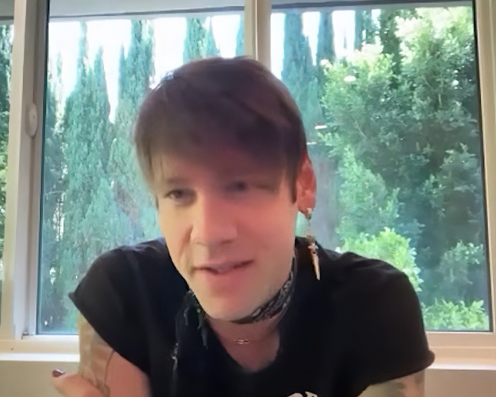 Rock star emerging unrecognizable after coming out as gay, talking in a video, looking natural and relaxed.