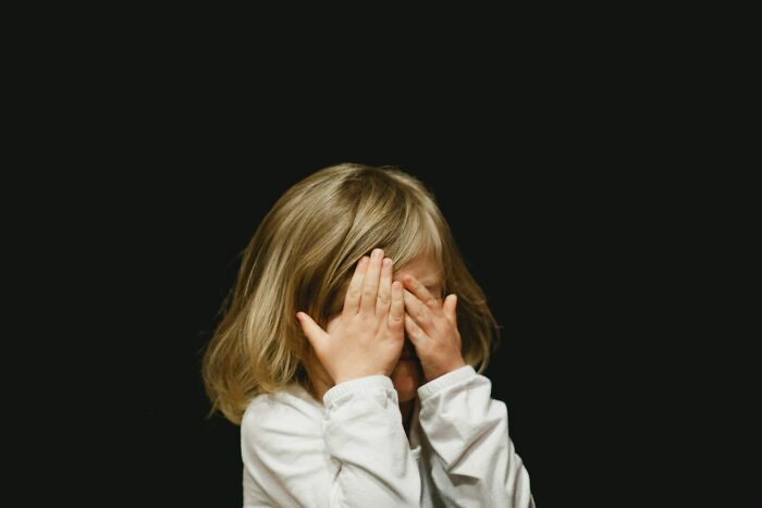 A young child covers their eyes in fear, evoking scary true stories and questioning reality.