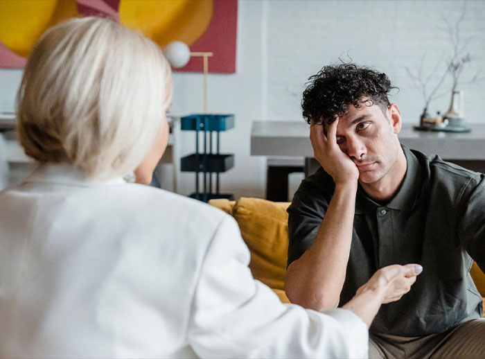 A man looking distressed while a woman talks to him, representing the tension from in-laws marriage advice. A man looking distressed while a woman talks to him, representing the tension from in-laws marriage advice.
