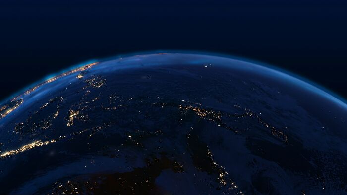A nighttime view of Earth from space, showing city lights, revealing scary science facts about our planet's scale.