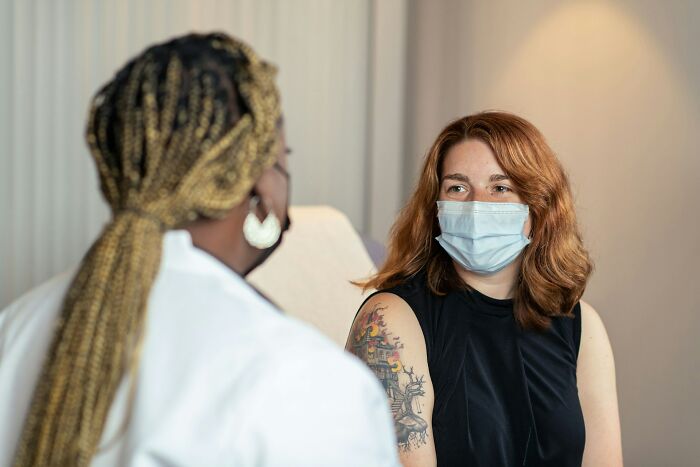A female patient in a mask listens to a doctor during a consultation, representing challenging medical diagnoses.