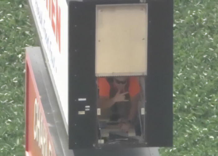 Close-up of a terrified electrician stuck inside a tall sign, recording a goodbye message.