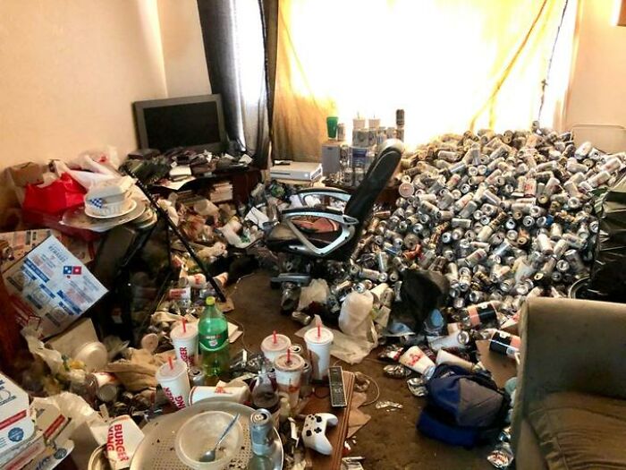 A truly messy male living space overflowing with trash, empty cans, and fast-food containers creating an unhygienic environment.