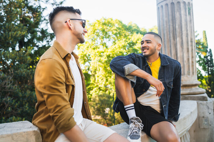 Two men smiling and talking outdoors, representing diverse reasons for affair partners.
