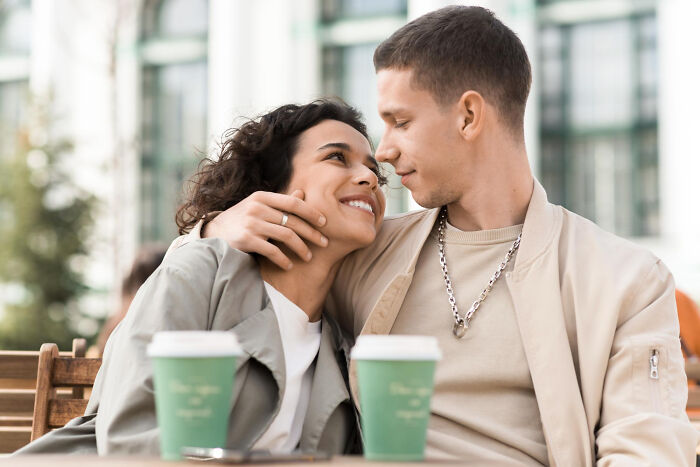 A couple looking lovingly into each other's eyes at an outdoor cafe, discussing affair partners.