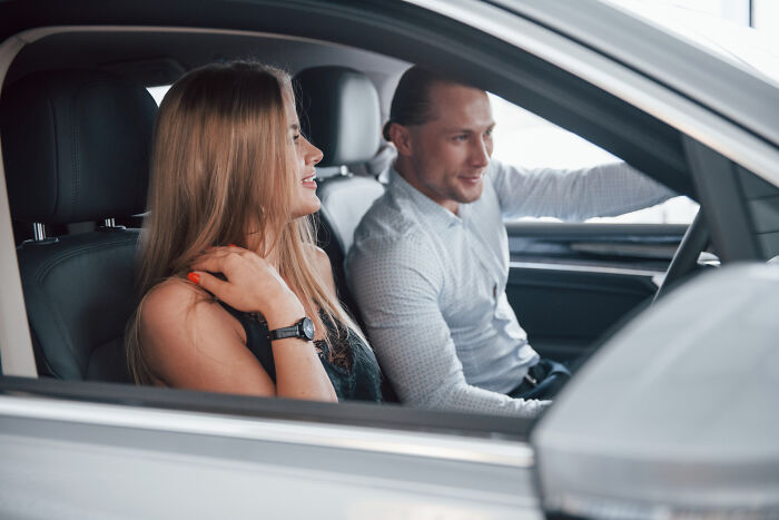 A couple in a car, looking at each other, possibly on their way to meet affair partners.