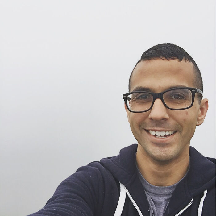 A man with glasses smiling in a foggy outdoor setting, representing a trip that didn't go exactly as planned with a obscured view.