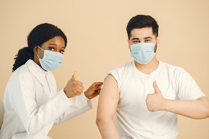 A nurse administers a vaccine to a man, both giving thumbs up. Insider knowledge on health industries.