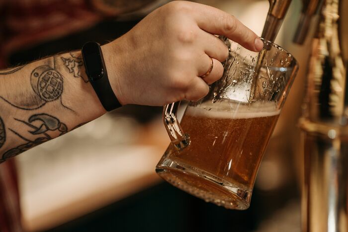 A tattooed bartender pouring beer, providing insider knowledge from the hospitality industry, highlighting different industries.