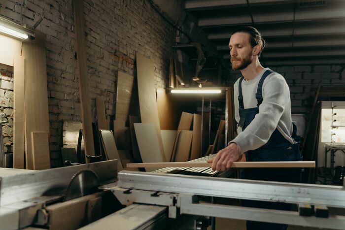 A craftsman in a workshop using a table saw to cut wood. Explore insider knowledge from different industries.