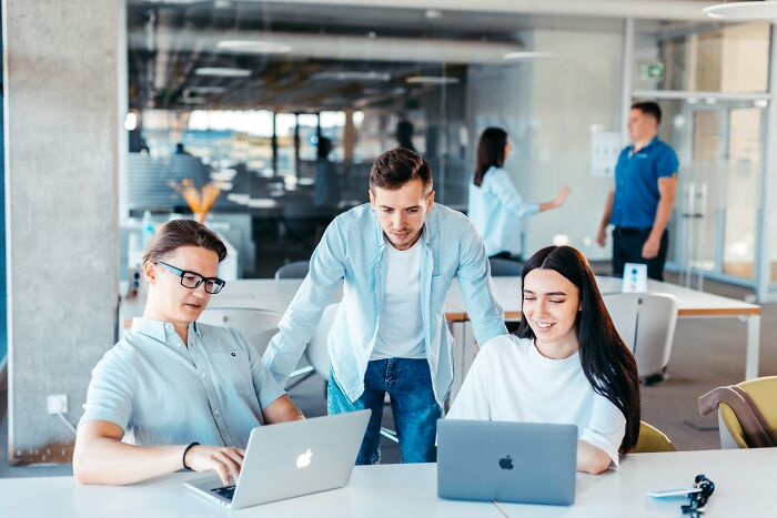 Three colleagues working on laptops in an office, collaborating with insider knowledge from different industries.
