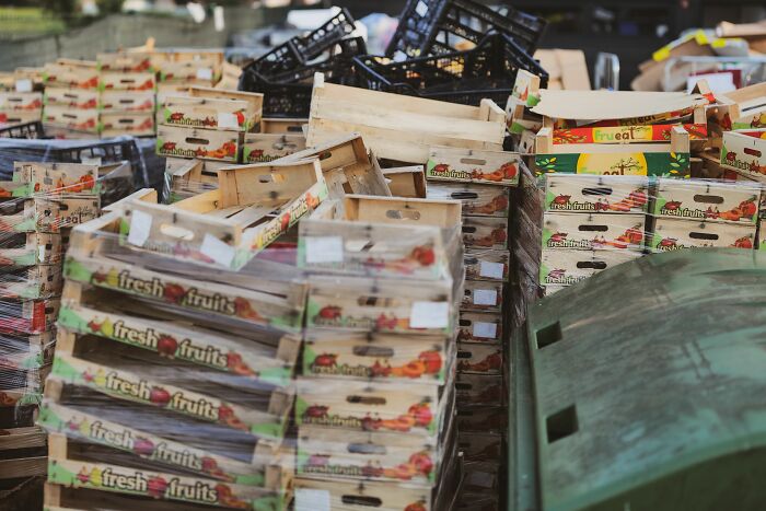 Stacks of empty wooden and plastic crates with 'fresh fruits' labels, showing insider knowledge of the food industry.