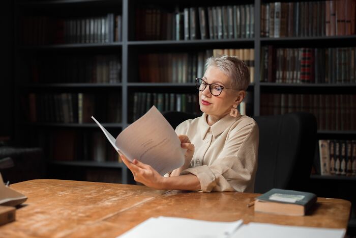A librarian reading a book in a library, reflecting insider knowledge in the literary world.