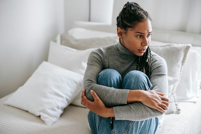 A woman sitting on a bed, looking thoughtful, reflecting on insider knowledge from different industries.