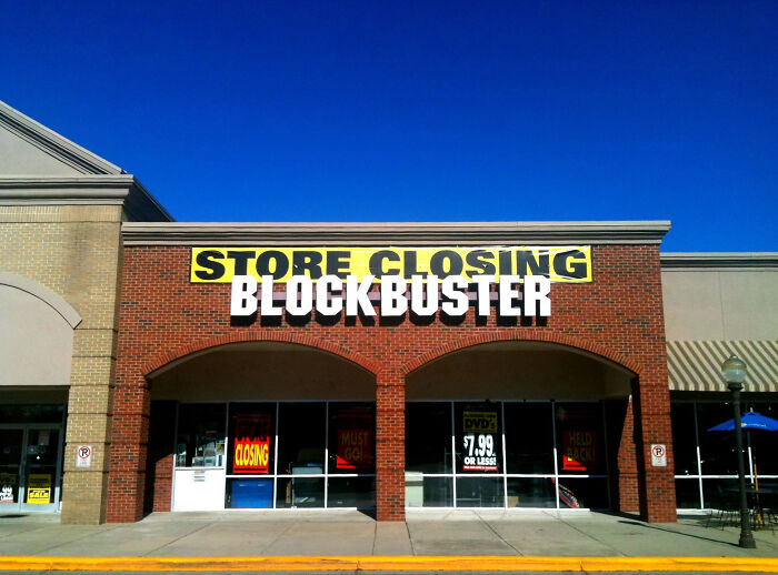 A Blockbuster store with a 'Store Closing' sign, symbolizing companies that used to dominate the market but failed.
