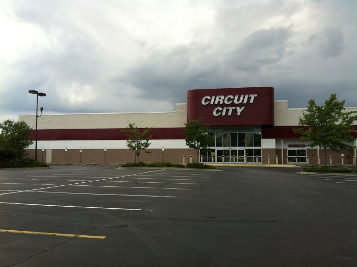 The exterior of an empty Circuit City store with a large parking lot, showing a company that used to dominate the market.