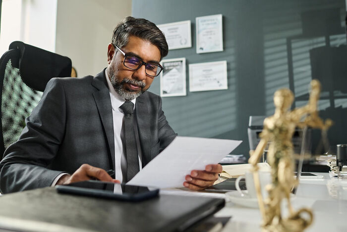 A lawyer reviewing documents in an office, symbolizing decisions that can lead companies to ruin or success.