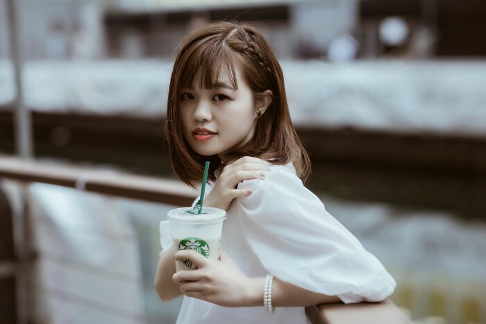 A young woman holding a Starbucks drink, a company that has managed to dominate the market.