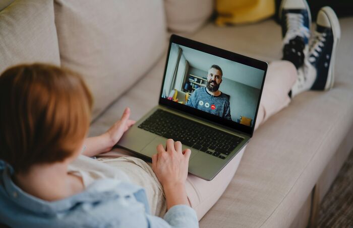 A person lounges on a couch, engaged in a video call on a laptop, depicting companies' changing communication.