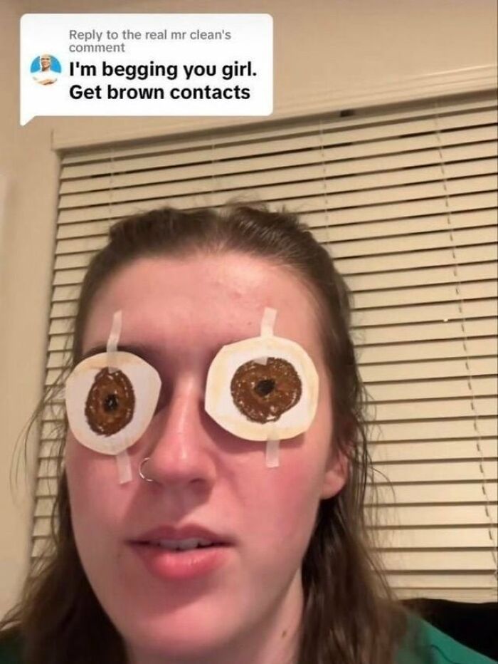 A girl with paper brown contacts taped over her eyes, an example of dumb people and low IQ.