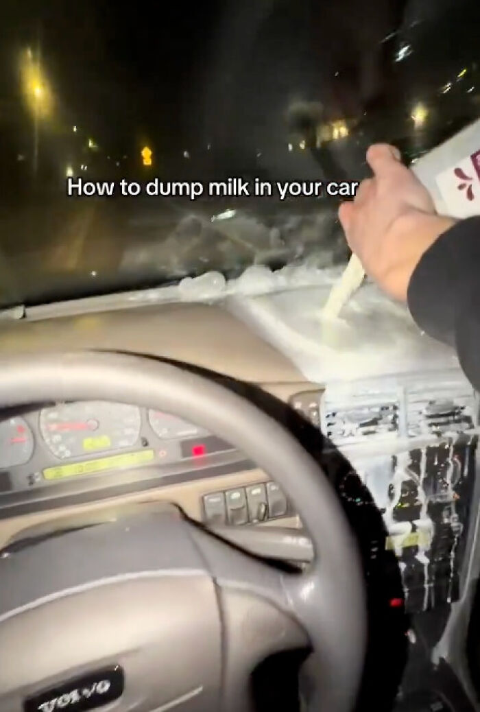 Someone pouring milk inside a car, an example of dumb people making a mess in their vehicle.