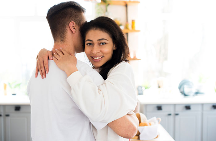 A happy couple embracing in a bright kitchen, where a guy's mom uses vitiligo as an insult.
