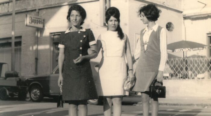 Three women wearing classic vintage beauty attire and accessories standing outside with a car in the background. Three women wearing classic vintage beauty attire and accessories standing outside with a car in the background.