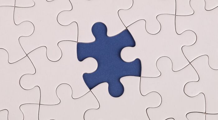 A close-up of a white jigsaw puzzle with one missing piece revealing a blue background, perfect for a vocabulary challenge.