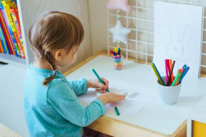 Teachers were terrified of students, depicted by a young child drawing at a desk, showing innocence.