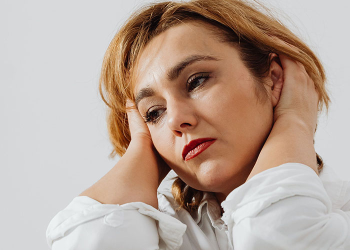A woman with short hair and red lipstick, looking down with a sad expression, showing how women caught their soulmates cheating.