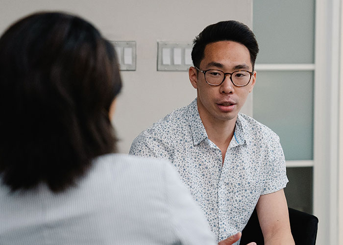 A man in glasses talking to another person, illustrating how women caught their soulmates cheating.