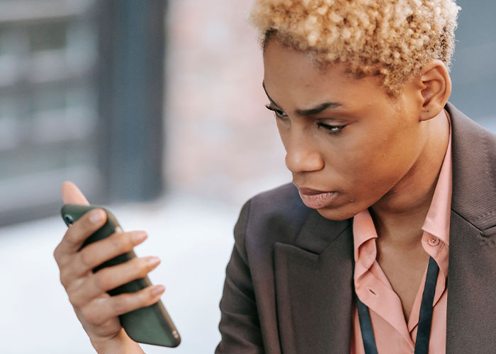A woman with blonde hair intently looking at her phone, depicting ways women caught soulmates cheating.