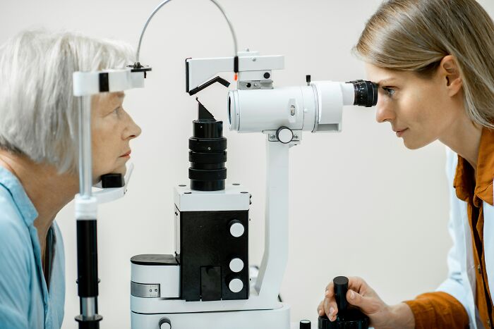 Female optometrist examining a senior woman's eyes, an example of doctor care.