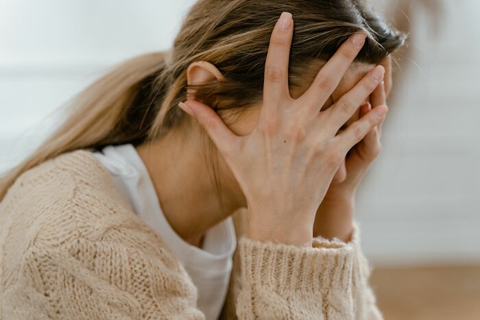 A woman covers her face with her hands, looking distressed, highlighting unhinged things doctors say.