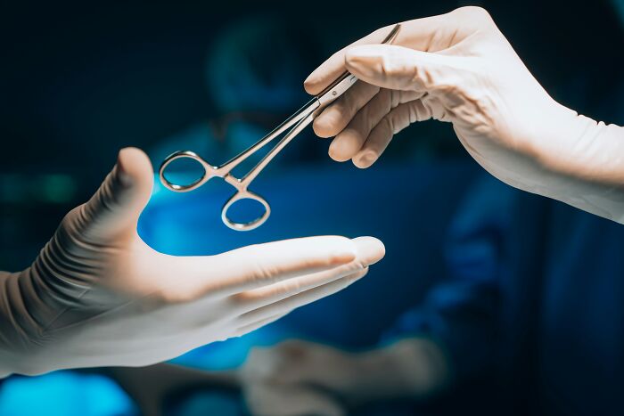 Two gloved hands exchange surgical instruments, illustrating medical procedures and sometimes unhinged things doctors say.