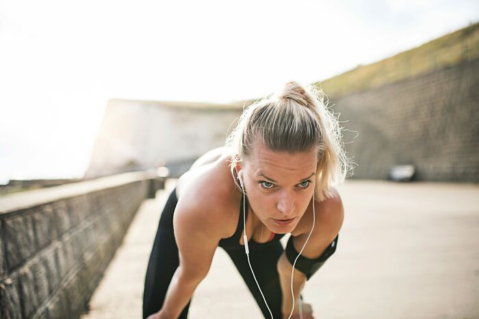A woman is taking a break during a run, breathing heavily. This relates to doctors saying unhinged things.