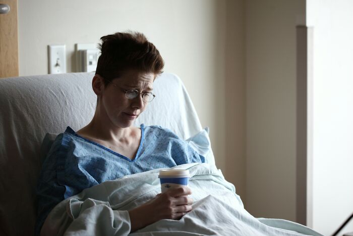 A patient in a hospital bed looks distraught, holding a cup. This illustrates the unhinged things doctors say.