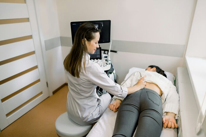 A doctor performs an ultrasound on a patient lying on an examination bed, representing medical care and unhinged doctor comments.