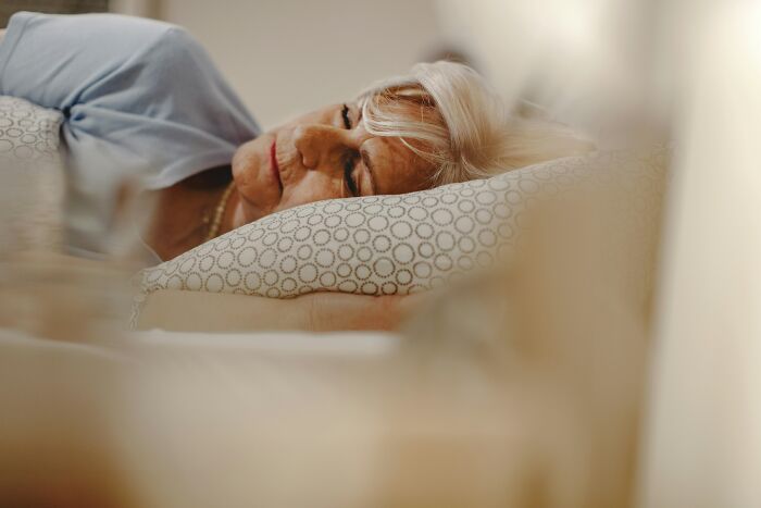 An older woman sleeping peacefully in bed, hopefully without dreams of claw marks or strange experiences.
