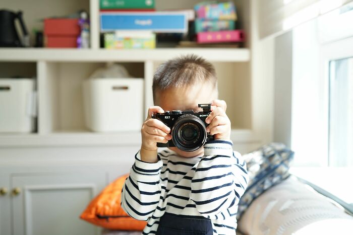 A young child holding a camera, aiming it forward, capturing strange experiences that make people shiver.
