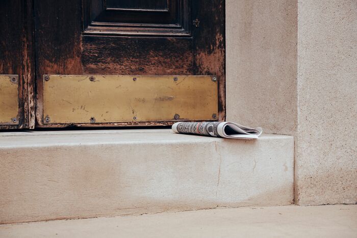 A newspaper left on the steps of a wooden door, perhaps part of a strange experience that makes people shiver.