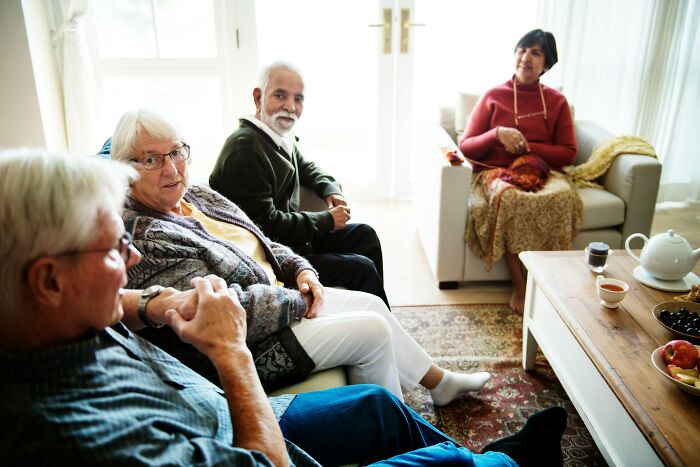 A group of older adults sitting in a living room, perhaps sharing memories of strange experiences that still make them shiver.