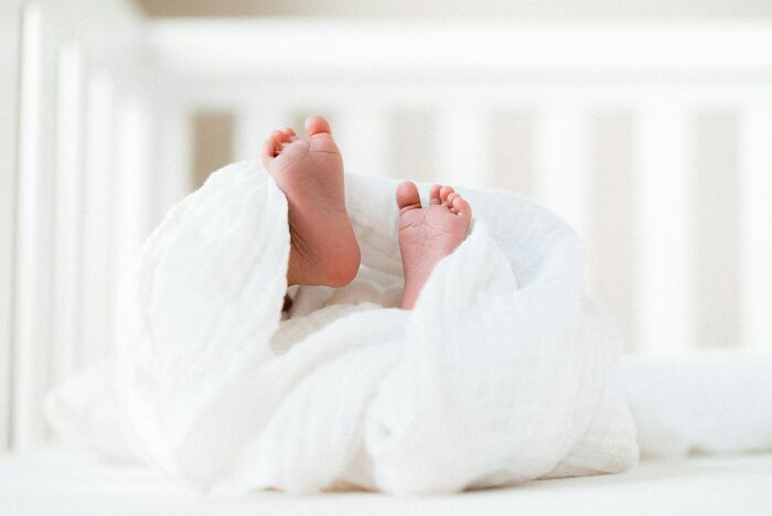 Tiny baby feet wrapped in a white blanket, a sweet image that offers comfort from strange experiences.