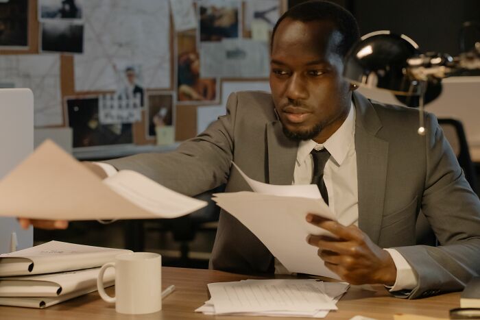 A man in a suit looking at documents, perhaps investigating strange experiences that make people shiver.