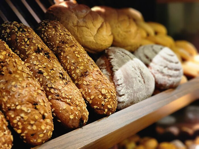 Various loaves of bread, some with oats, on a wooden shelf, a strange experience for the uninitiated.