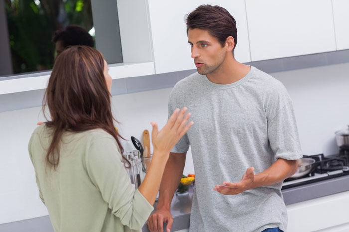 A couple arguing in a kitchen, representing a wife obsessed with a criminal trial getting mad.