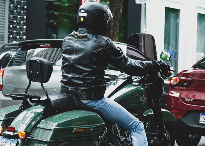 A person in a black leather jacket and helmet riding a motorcycle, often associated with midlife crises.