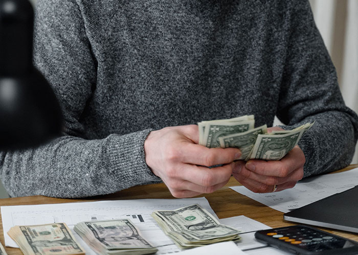 A person counting money at a desk, reflecting financial aspects of midlife crises.