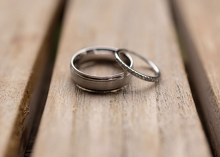 Two wedding rings on a wooden surface, symbolizing relationships and potential midlife crises.
