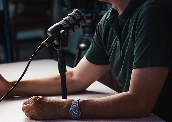 A man speaking into a microphone, potentially discussing or experiencing a cringe midlife crisis.